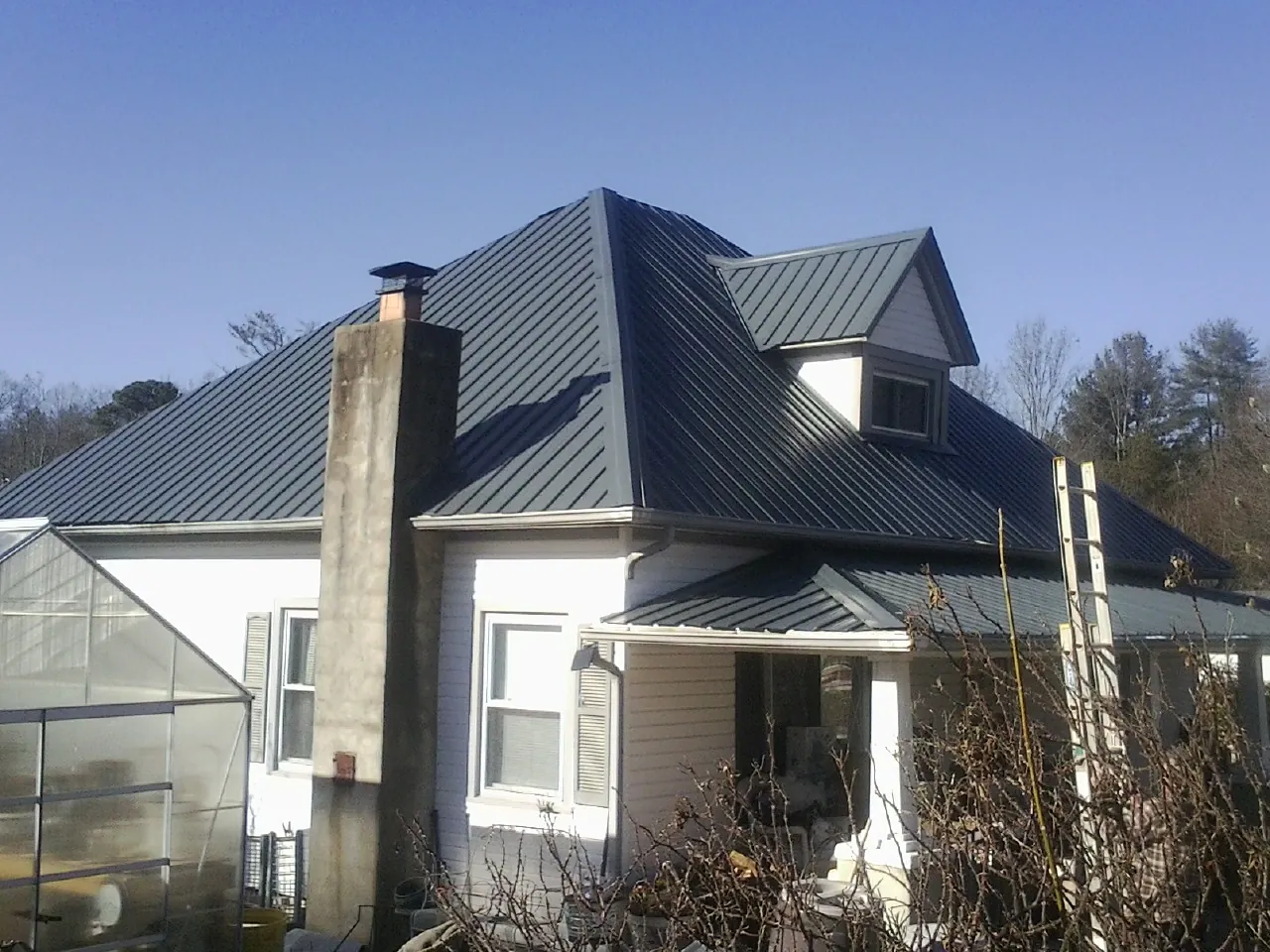 Dark blue standing seam metal roof on a white farmhouse with dormer — Slate & Tile Roof Repair by Roofing Brothers in Effingham