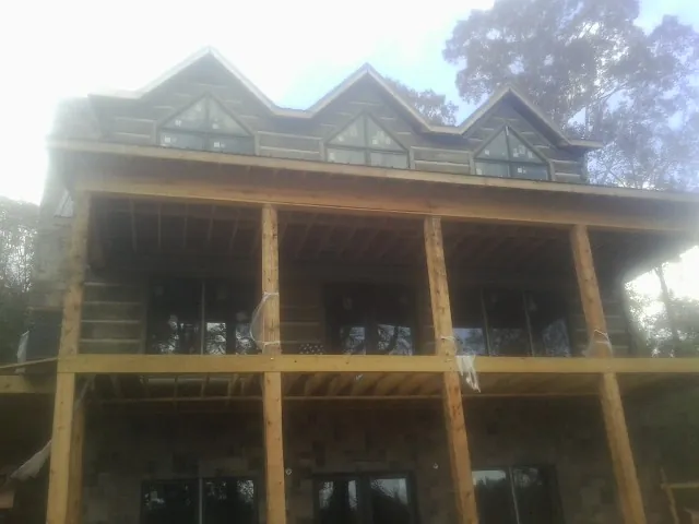 Dormers and porch framing on a large log home under construction — Roof Coating work by our crew in Effingham