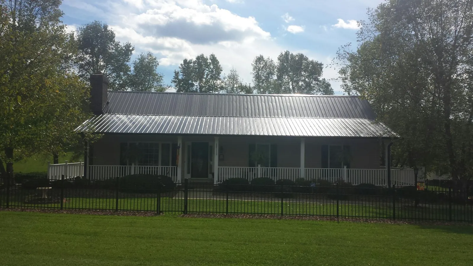 Gray metal roof on a brick ranch with a full width front porch — Gutter Guard Installation work by our crew in Effingham