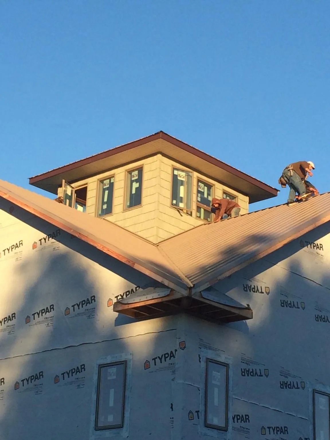 Roofers working around a rooftop cupola on a new metal roof at sunset — Roof Waterproofing in Effingham by Roofing Brothers